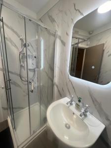 a bathroom with a shower and a sink and a mirror at Central Bar Guesthouse in Cushendall +28 photos