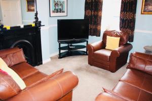 a living room with leather furniture and a flat screen tv at Central Bar Guesthouse in Cushendall