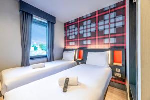 two beds in a room with a window at easyHotel Dublin in Dublin