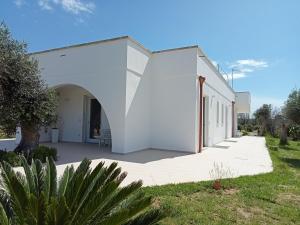 a white building with an arch in a yard at Villa Bello camere in Giurdignano +17 photos