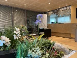 a lobby with flowers and plants in a room at Hotel des Congrès in Villeurbanne