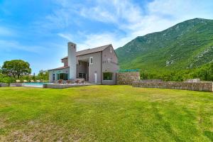 a house with a grassy yard in front of a mountain at Villa Jure - Heated Pool, Sauna, Tennis & Mini Golf I Dalmatia Hinterland in Župa