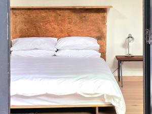 a bed with white sheets and a wooden headboard at River Star Retreat in Zuurbraak