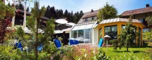 ein Haus mit Garten und blauen Stühlen im Hof in der Unterkunft Boutique Hotel Dorer in Schönwald