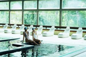 two women sitting on the edge of a swimming pool at Hotel Villa Pina in Milano Marittima