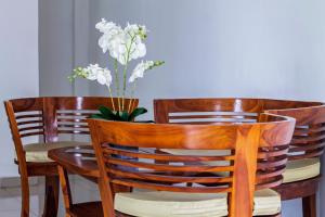 een houten tafel met een vaas met witte bloemen erop bij RedDoorz @ Jatiwaringin in Jakarta