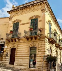 an old building with green shuttered windows and balconies at La Corte di Noto in Noto