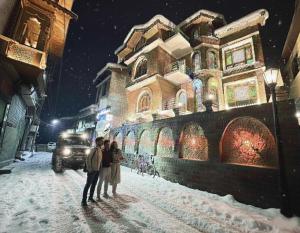 a couple standing in the snow in front of a building at Faizzy residency in Srinagar