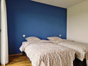 two beds in a bedroom with a blue wall at Chambres d'hôtes La Ganivelle in Servant