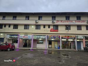 a building with a car parked in a parking lot at Hotel Shreejay Lodging in Mahād