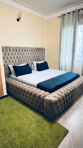 a large bed with a large tufted headboard in a bedroom at Modest Spacious Apartment in Kampala