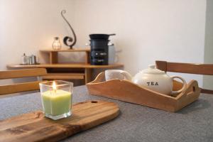 a candle on a wooden tray with a tea set on a table at Casa Arcobaleno in Airolo +9 photos