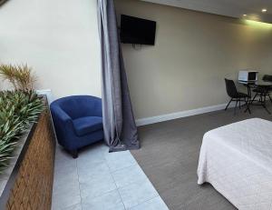 a bedroom with a blue chair and a tv at Sisleys Motel in Lismore