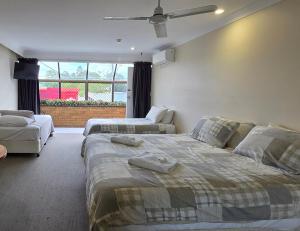 a bedroom with two beds and a ceiling fan at Sisleys Motel in Lismore