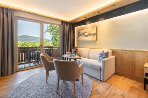 a living room with a couch and a table with chairs at Hotel Königgut in Wals