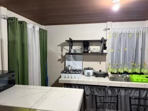 a kitchen with a stove and a green curtain at Ticary Nature Homes in Guápiles