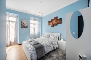 a bedroom with blue walls and a bed and a mirror at Casa da Ponte in Lombinha
