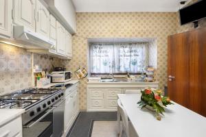 a kitchen with white appliances and a window with flowers on the counter at Casa da Ponte in Lombinha