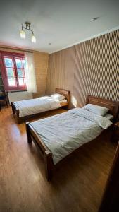 two beds in a room with two windows at Mohh prostir vidpochinky in Mohnate