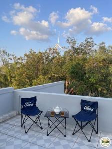 two chairs and a table on a balcony with a wind turbine at Ánh Dương Local Mini Tour in An Lợi (4)