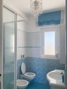 a bathroom with a toilet and a sink and a chandelier at Fiorucci Apartments - Veronica's House Fiumicino in Focene +11 photos