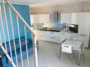 a kitchen with white cabinets and a table at Fiorucci Apartments - Veronica's House Fiumicino in Focene