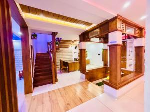 a living room with wooden floors and a staircase at THE iVORY VILLA in Kottayam