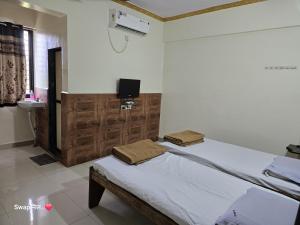 a bedroom with a bed and a tv on a wall at Hotel Shreejay Lodging in Mahād