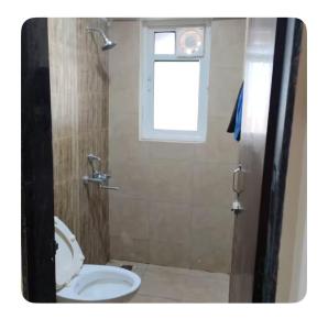 a bathroom with a toilet and a window at The Aura stays in Indore