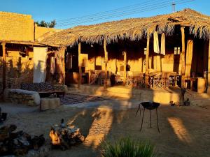 a building with a straw hut with tables and chairs at Grand Siwa in Siwa