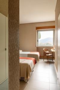 two beds in a room with a window at Hotel Al Sant'Andrea in Sarzana