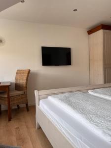 a bedroom with a bed and a chair and a tv at Weingut Zenz-Pohl in Kinheim