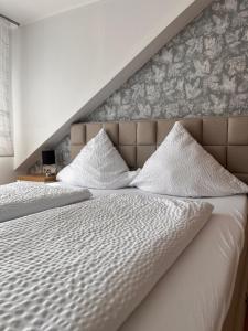two beds with white sheets and pillows in a bedroom at Weingut Zenz-Pohl in Kinheim