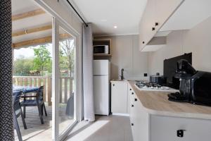 a kitchen with white cabinets and a table with a dining room at Mobilehome riviera avec terrasse 48 in Saint-Gervais +15 photos