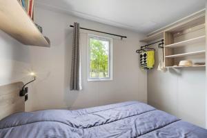 a bedroom with a bed and a window at Mobilehome riviera avec terrasse 48 in Saint-Gervais