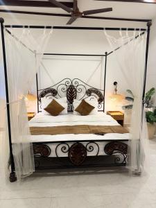a bedroom with a black canopy bed with pillows at cali stays in Chapora