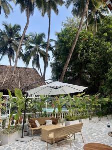 a patio with an umbrella and chairs and palm trees at cali stays in Chapora