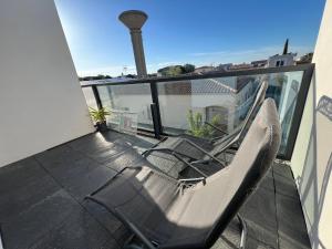 a pair of chairs sitting on a balcony at Les Appartements chez Hanene in Le Grau-du-Roi