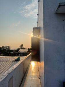 a sun setting over a white wall with a sidewalk at Ánh Dương Local Mini Tour in An Lợi (4)