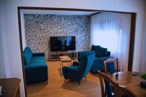 a living room with blue chairs and a flat screen tv at Lavanda Lux in Drvar