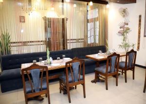 a dining room with two tables and a blue couch at Hotel Yadu Residency in Meerut