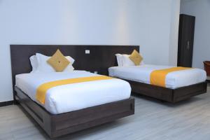 two beds with orange and white sheets in a room at yellow apple hotel in Addis Ababa +6 photos