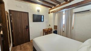 a bedroom with a bed and a flat screen tv at Hotel Labranza in San Martín de Valdeiglesias