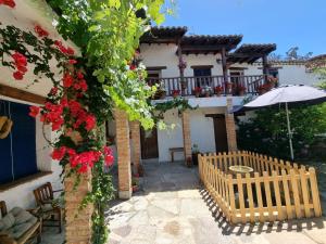 a house with a bench and an umbrella and flowers at Hotel Labranza in San Martín de Valdeiglesias