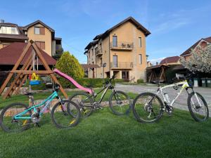 three bikes parked in the grass in front of a house at Pensiune Diana in Baile Felix