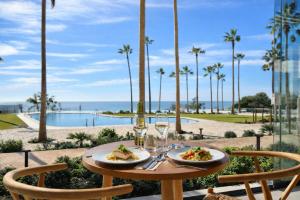 a table with two plates of food and a view of the ocean at Hotel Punta Bermeja Premium in El Puerto de Santa María