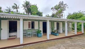 a house with a porch with tables and chairs at chez mamie in Les Avirons