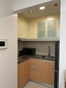 a kitchen with wooden cabinets and a black refrigerator at Resorts World Eighty One Newport Boulevard Near Airport T2 and T3 in Manila
