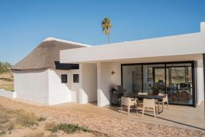 a thatch roofed house with a table and chairs at De Wildeveldt in Darling
