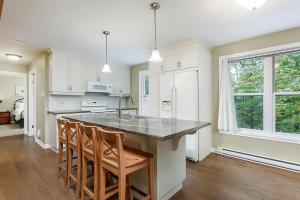 a kitchen with white cabinets and a island with bar stools at Ideal getaway - Ideal retreat in Lac-Brome +44 photos